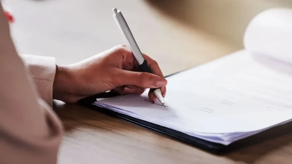 Ecommerce: How to build an online store with technology, user experience and artificial intelligence Mano escribiendo en documentos, simbolizando la importancia de políticas claras y accesibles en tiendas en línea para generar confianza en el usuario.